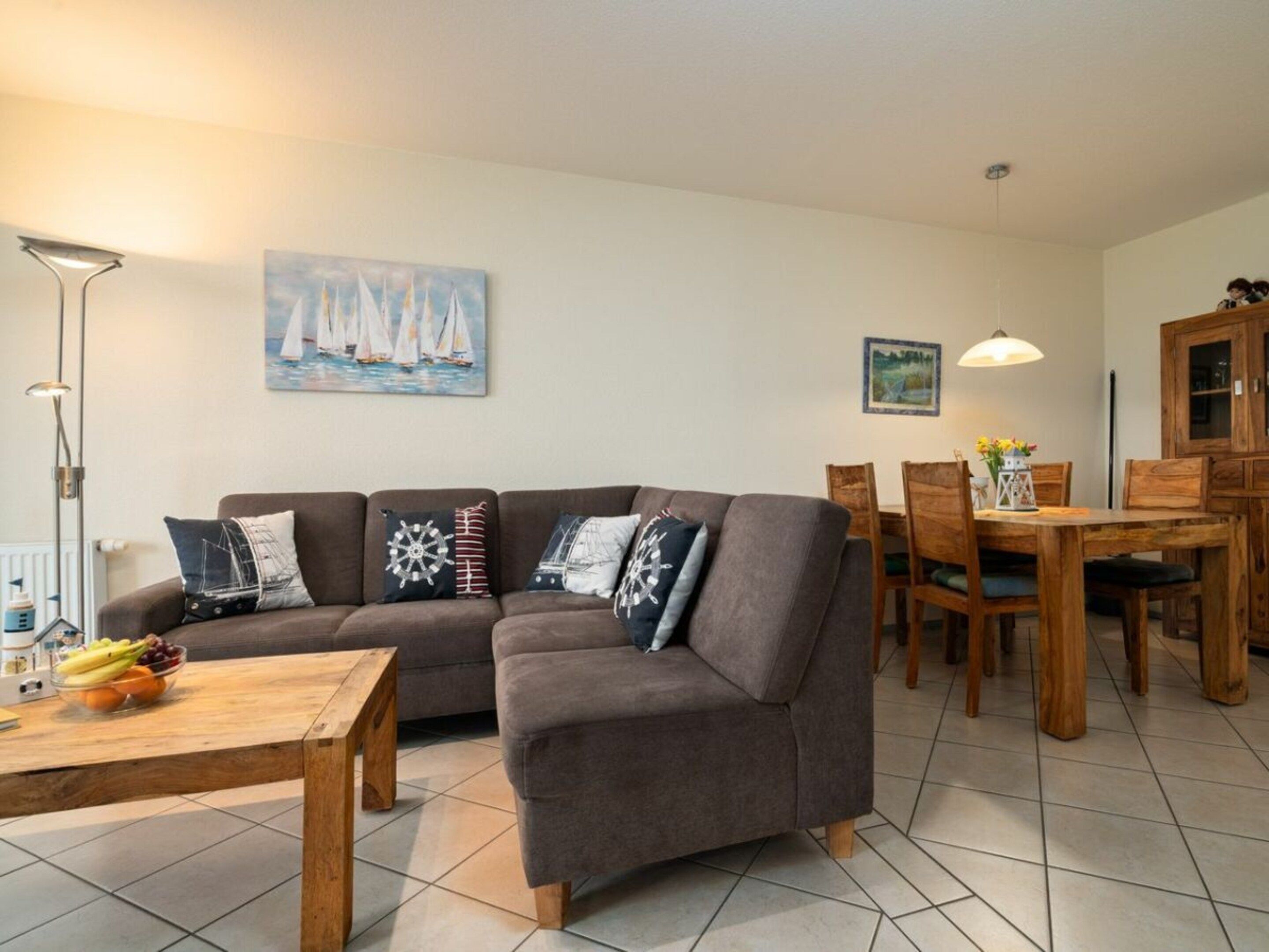 A living room with a sofa, a dining table, chairs, and a fruit bowl.