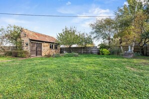 A stone building with a red roof, a fenced yard, and a statue. - Hot Tub & Games Room | Sleeps 11 | 4BR Wyboston (Wyboston)