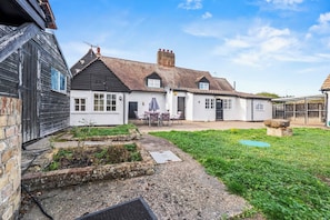 A traditional house with a patio, a small garden, and a clear sky. - Hot Tub & Games Room | Sleeps 11 | 4BR Wyboston (Wyboston)