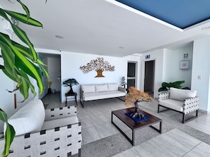 Una sala de estar moderna con un sofá, sillas, una mesa de centro y plantas decorativas.