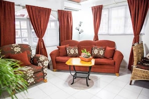 A living room with a sofa, armchair, and a small table with a plant. - Unique Aruban Retreat | 4BR in Bakval (Noord)