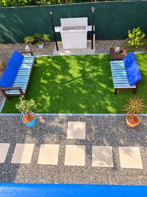 Eine Terrasse mit zwei Liegestühlen, einem kleinen Grill und Topfpflanzen.