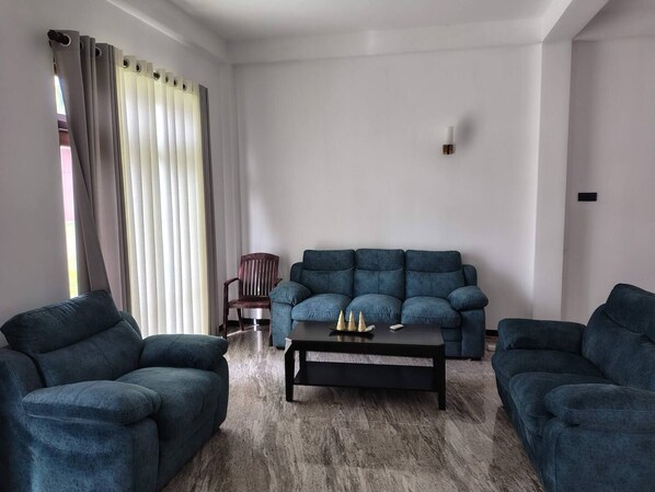 Een woonkamer met een bank, twee fauteuils, een salontafel en een stoel.