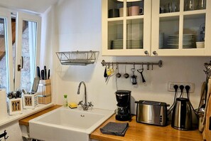 A kitchen with a sink, a coffee maker, a toaster, and cabinets above. - New Listing (Rab)
