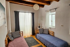 A small, cozy room with two single beds, a wooden ceiling, a window with curtains, and a small table with a lamp. - New Listing (Rab)