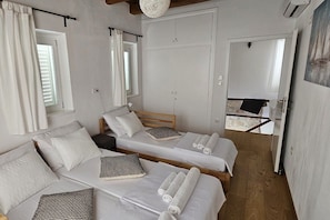 A room with two beds, a wooden ceiling, a large mirror, and a door leading to a bathroom. - New Listing (Rab)
