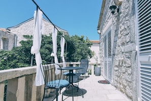 A balcony with outdoor seating, a stone wall, and a clear sky. - New Listing (Rab)