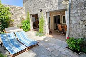 A stone building with a patio area featuring lounge chairs and a table. - New Listing (Rab)