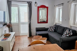 A living room with a sofa, a dining table, a coffee table, and a mirror on the wall. - New Listing (Rab)