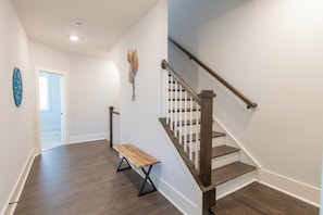 A modern interior with a wooden staircase, a bench, and a decorative wall piece. - Charlotte Retreat - Hot Tub, Games & Near Uptown (Charlotte)