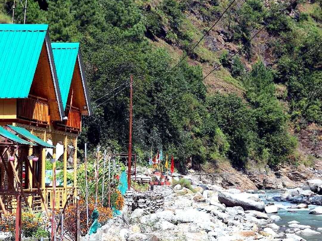 Une structure en bois avec un toit bleu, située près d’une rive rocheuse.