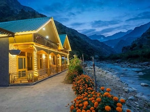A hotel with a balcony overlooking a river, surrounded by mountains. - Himalayan River Nook Cottages (Sainj)