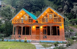 A two-story wooden house with a balcony, set in a mountainous area. - Himalayan River Nook Cottages (Sainj)