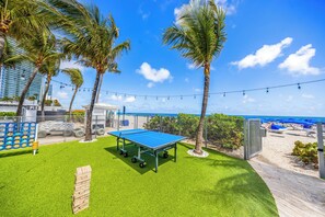 Une table de billard, des palmiers, une plage et une clôture.