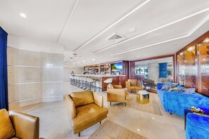 Un hall d’hôtel moderne avec un bar, des canapés en cuir et un sol en marbre.