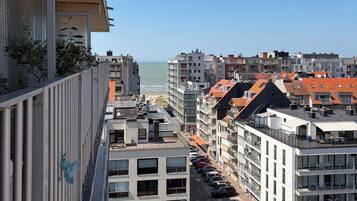 Un immeuble de grande hauteur doté de balcons donnant sur une rue et une plage.