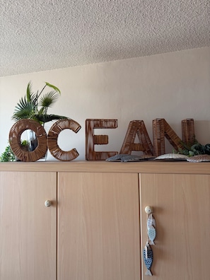 A wooden cabinet with a decorative word 'OCEAN' on top, a plant, and a fish ornament. - New Listing (Nieuwpoort)