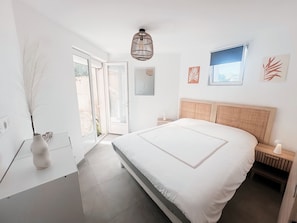 Une chambre à coucher avec un grand lit, une table de chevet, une commode, un luminaire suspendu et une fenêtre donnant sur un beau paysage.