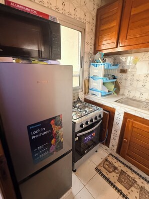 Une cuisine équipée d’un réfrigérateur, d’une cuisinière, d’un four à micro-ondes et de meubles de rangement en bois.