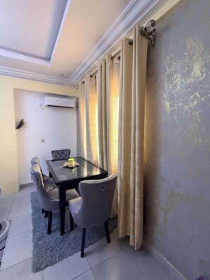 Un coin repas comprenant une table et des chaises, un luminaire au plafond et un climatiseur fixé au mur.