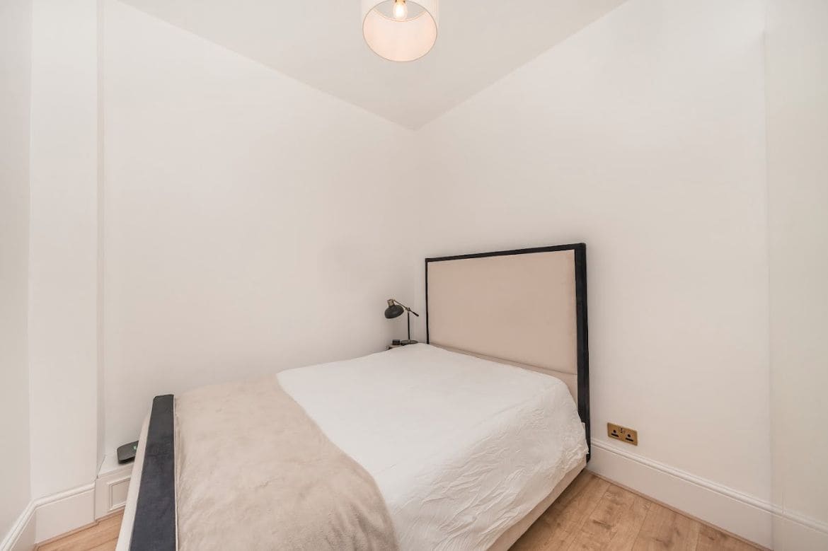 Une chambre à coucher minimaliste, avec un lit simple, une lampe de chevet et un luminaire au plafond.