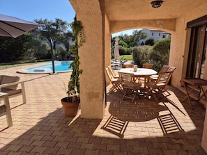 Eine Terrasss mit Pool, einem Tisch mit Stühlen und einem Blumentopf.
