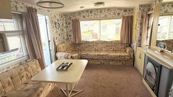 A compact living space with a sofa, a dining table, and a kitchenette area.