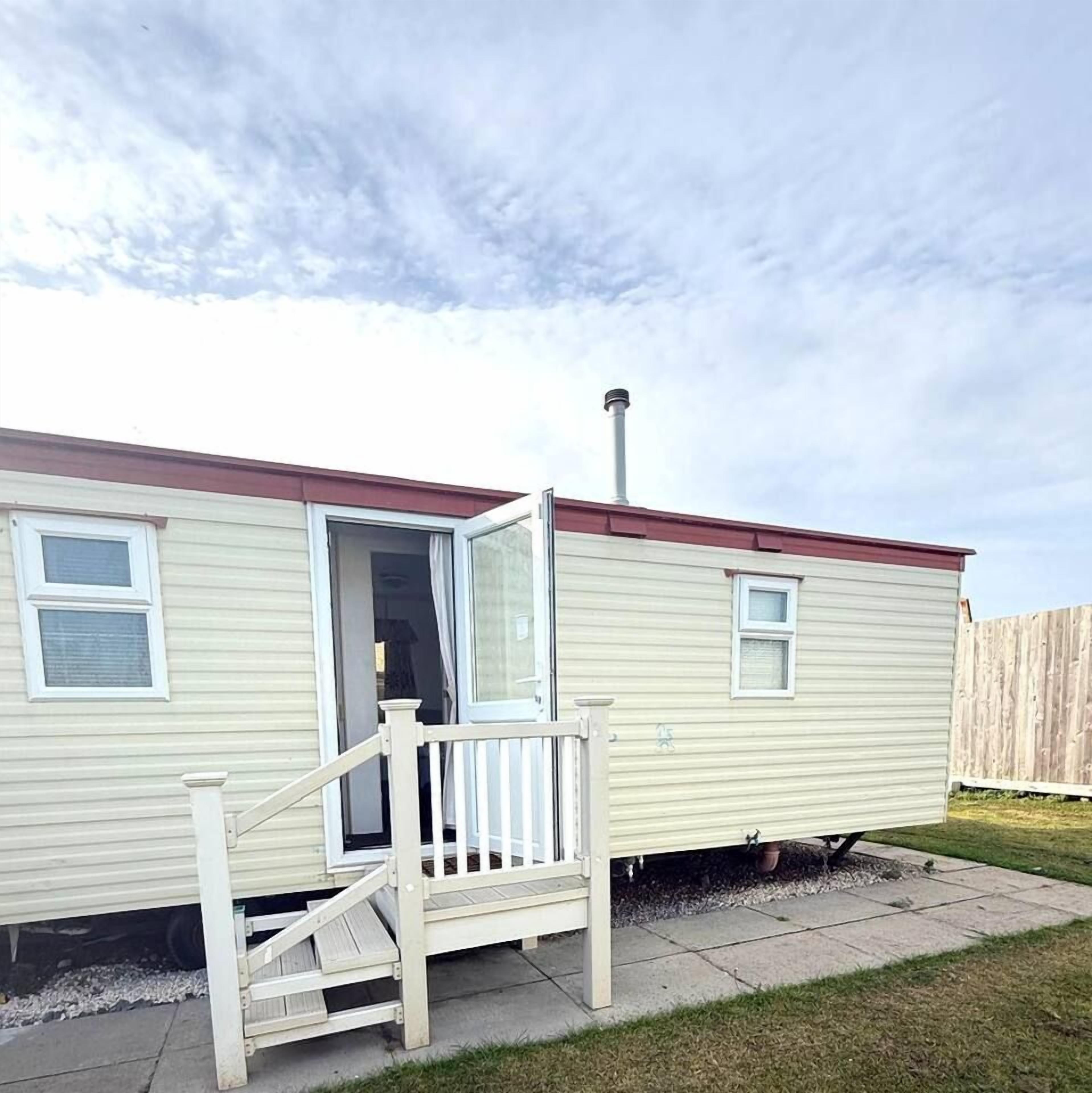 A mobile home with a front porch, a chimney, and a sliding door.