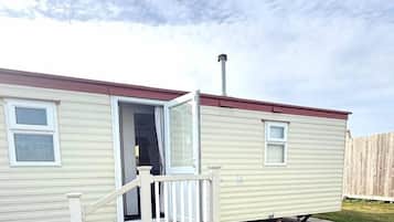 A mobile home with a front porch, a chimney, and a sliding door.