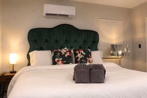 A hotel room with a large bed, a headboard, a bedside lamp, and a window with blinds. - Colorful Cottage • Less than 2mi to UGA (Athens)