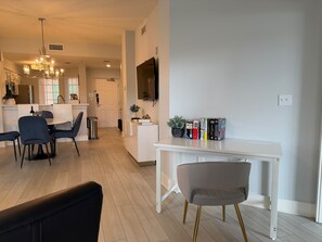 A modern kitchen with a dining area, a white table with books, and a chandelier. - Lakeside Serenity at Worldquest (Orlando)