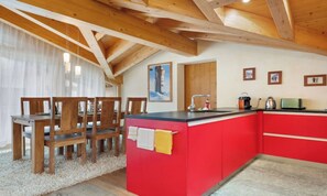 Una cucina con isola rossa, sedie di legno e un tavolo da pranzo.