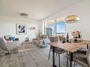 Ein modernes Wohnzimmer mit Essbereich, großem Fenster und Deckenleuchte.