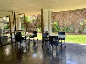 An outdoor patio area with a glass enclosure, a table with chairs, and a brick wall with greenery. - Smart Loft Home Office Laundry Parking (Santiago)