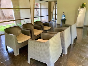 A seating area with wicker chairs and a table, a water dispenser, and a refrigerator. - Smart Loft Home Office Laundry Parking (Santiago)