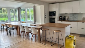 Eine moderne Küche mit einer Holztheke, Barhocker und Blick auf Grünfläche.