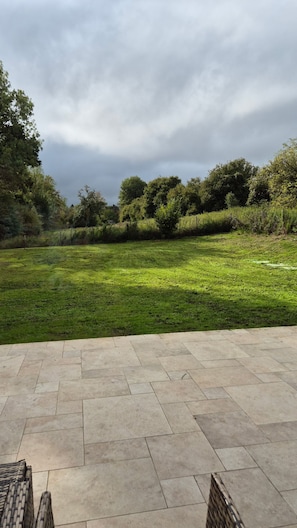 An outdoor patio area with a stone floor and a grassy field in the background. - Cosy villa so spacious near deauville (Surville)