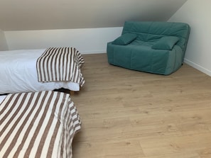 A room with a bed, a striped pillow, a teal armchair, and a wooden floor. - Cosy villa so spacious near deauville (Surville)