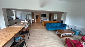 A spacious living area with a wooden dining table, blue sofa, and a TV in the background. - Cosy villa so spacious near deauville (Surville)