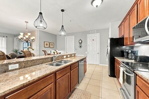 A kitchen with granite countertops, wooden cabinets, stainless steel appliances, and pendant lighting. - Work, Play and Stay, 3br, Prime Orlando Location (Orlando)