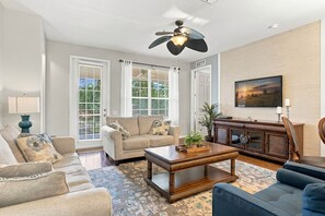 A living room with a sofa, armchair, coffee table, and a television on the wall. - Work, Play and Stay, 3br, Prime Orlando Location (Orlando)