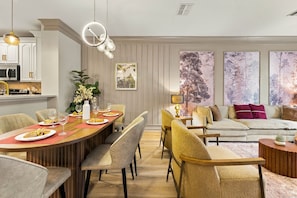 A modern living room with a dining area, featuring a sofa, chairs, a coffee table, and a dining table set with plates and glasses. - Stylish Vista Cay 3br, Comfort at a Prime Location (Orlando)