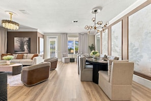 A spacious living room with a dining area, large windows, and a chandelier. - Upscale Vista Cay 3BR With Resort Pool View (Orlando)