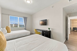 A hotel room with two beds, a desk, a chair, a TV, and a window with curtains. - Work and Play, Spacious 3BR at Vista Cay (Orlando)