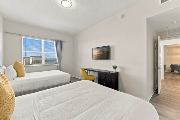 A hotel room with two beds, a desk, a chair, a TV, and a window with curtains. - Work and Play, Spacious 3BR at Vista Cay (Orlando)