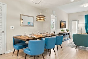 A dining area with a wooden table, blue chairs, and a pendant light. - Spacious 3br, Near Parks and Convention Center (Orlando)