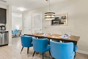 A dining area with a wooden table, blue chairs, and a hanging light fixture. - Comfortable 3BR Family Getaway, Top Location (Orlando)