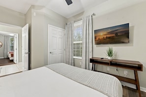 A bedroom with a bed, a bedside table, a window with curtains, a painting on the wall, and a door leading to another room. - Vista Cay 3br, Comfort & Prime Location, Sleeps 7 (Orlando)