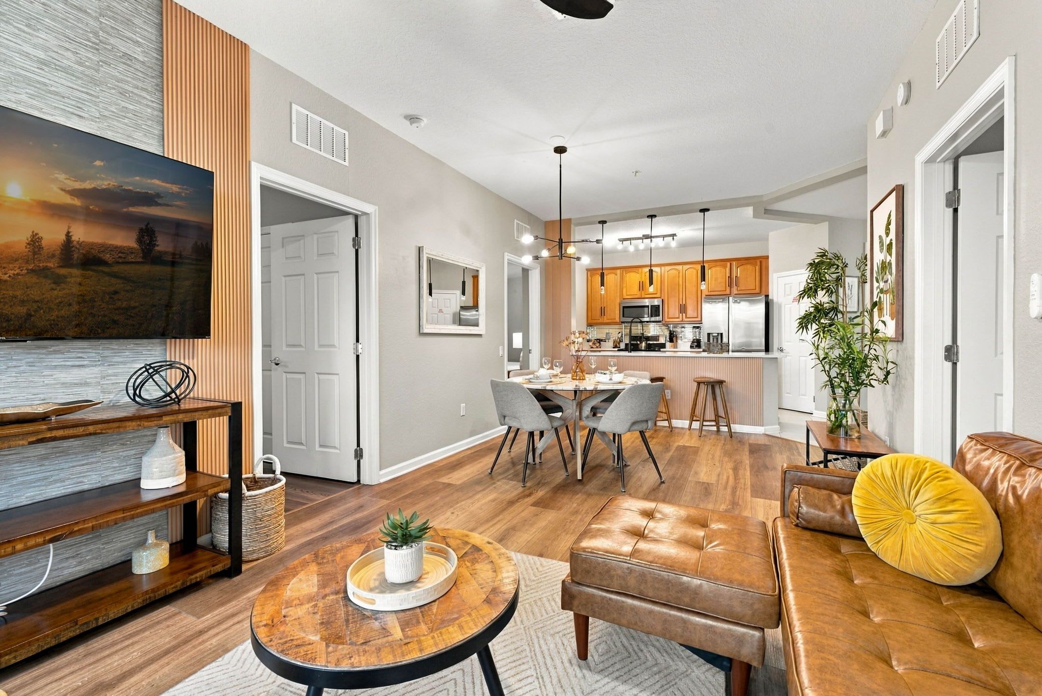 A modern living room with a TV, seating, and a dining area.