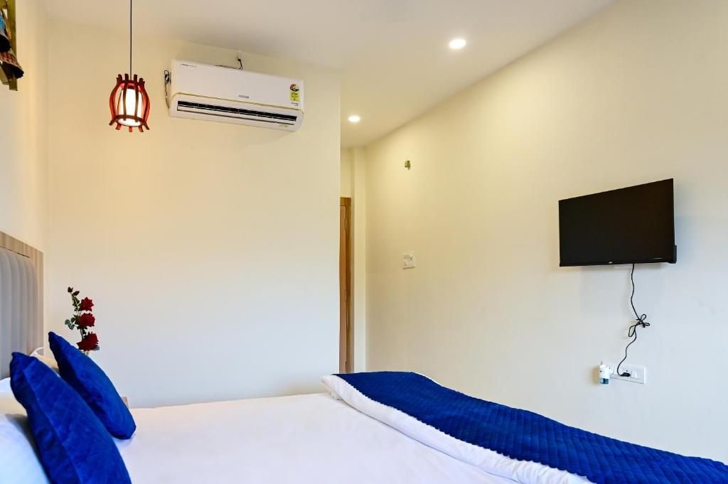 Une chambre d’hôtel équipée d’un lit, d’un téléviseur fixé au mur, d’un appareil de climatisation et d’un luminaire décoratif suspendu au plafond.